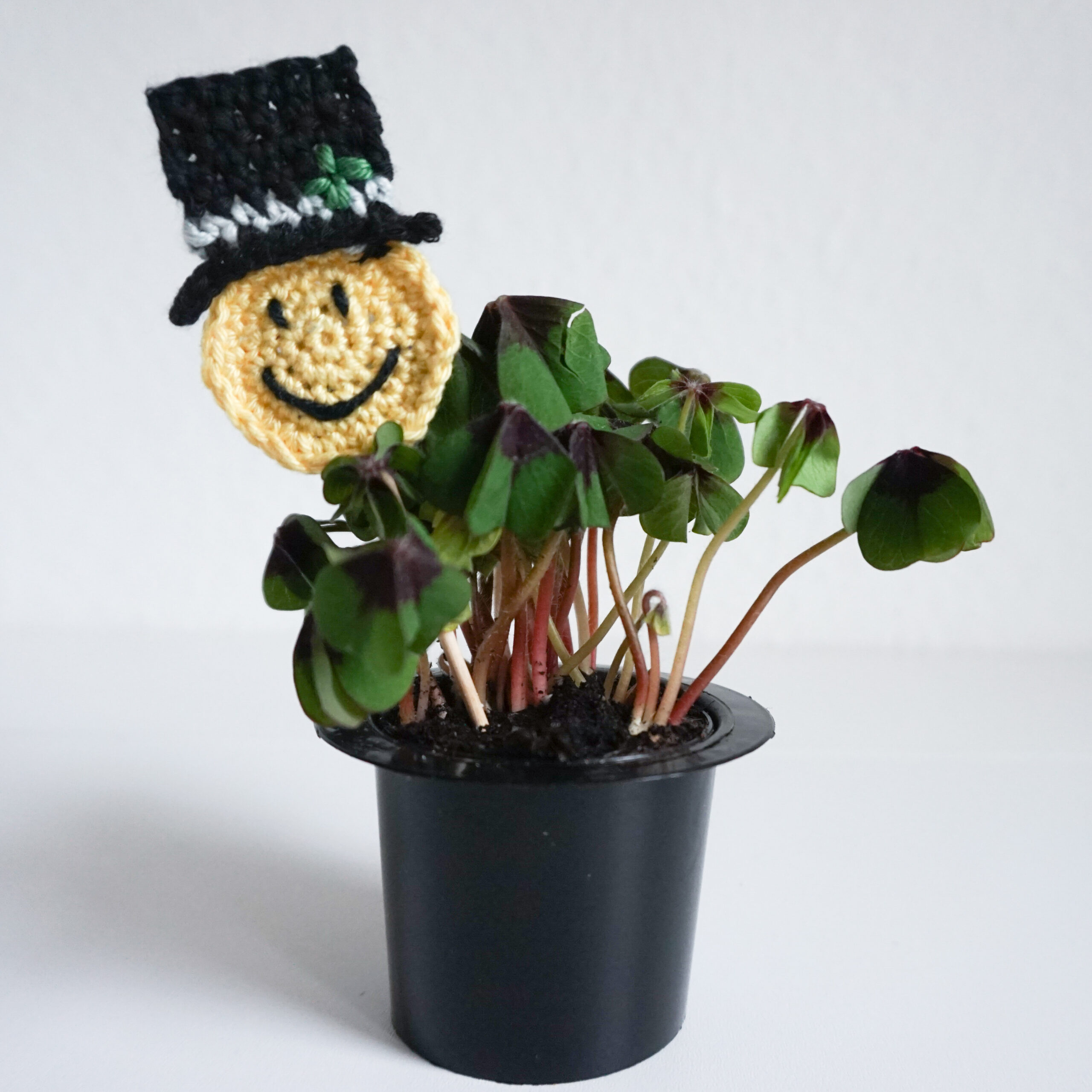 Häkeln für Silvester: Gehäkelter Schornsteinfeger als Blumenstecker in einem kleinen Topf mit Glücksklee